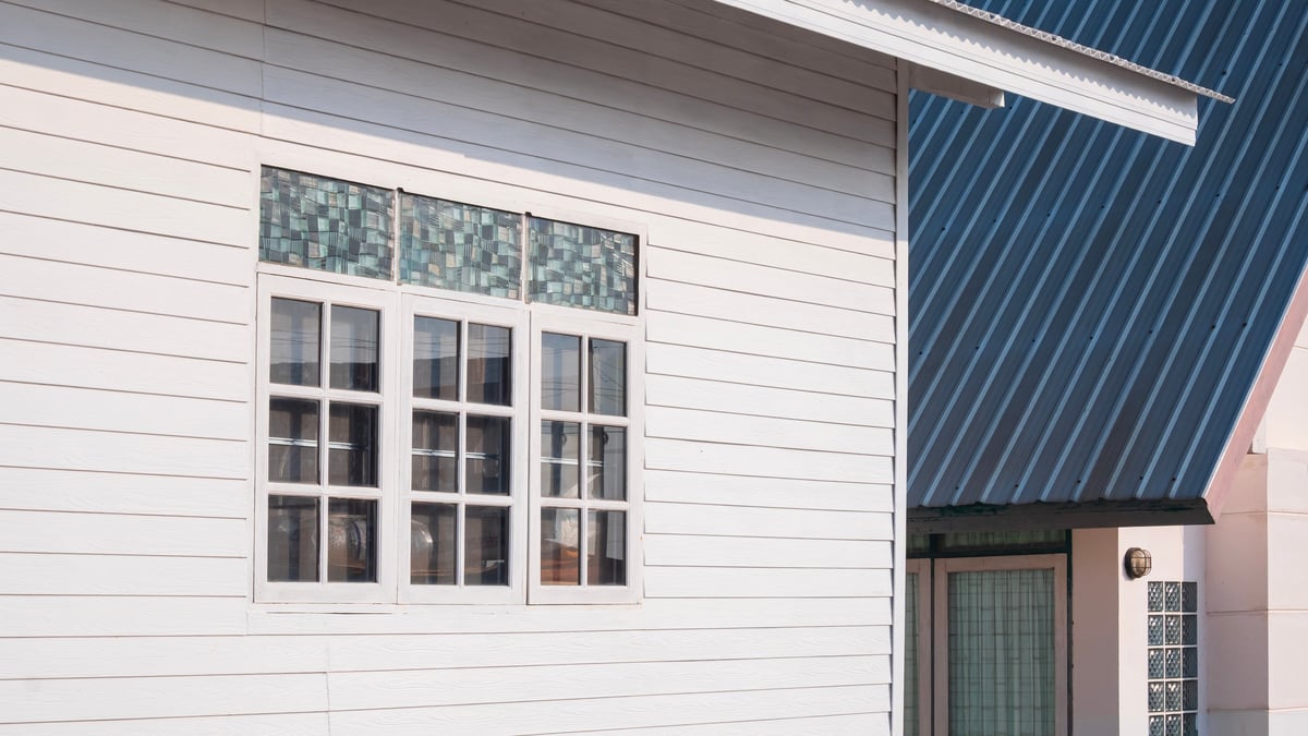 Newly built white home exterior with modern windows and corrugated metal roof detail under bright sunlight in Boise Idaho